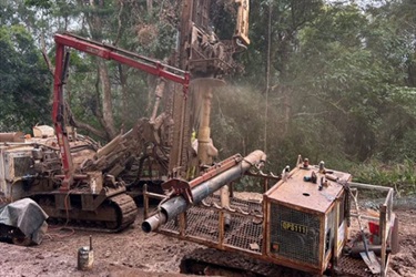 Large machine boring hole in dirt road.