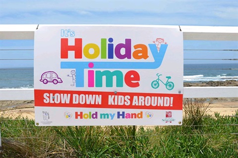 Holiday-time-road-safety-sign-on-fence-at-beach.jpg