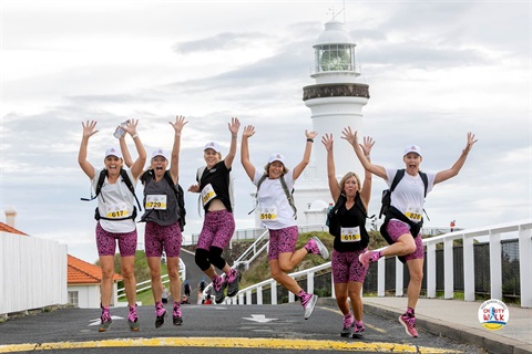 Walkers jumping for joy in front of the Byron Bay lighthouse