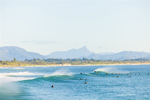 surfers sitting behind breaking waves in ocean