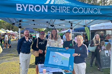Five people under marquee and holding sign