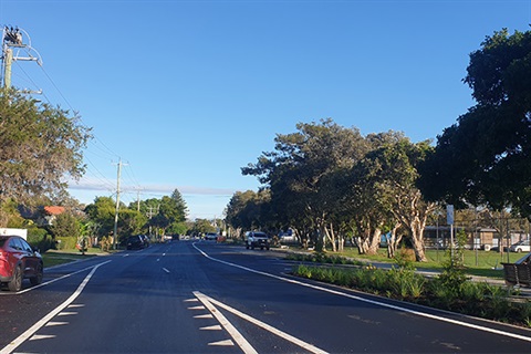 Asphalt road with gardens and angle parking spaces on right and parallel parking spaces on left 