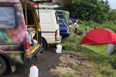 Vans lined up on the reserve with tents