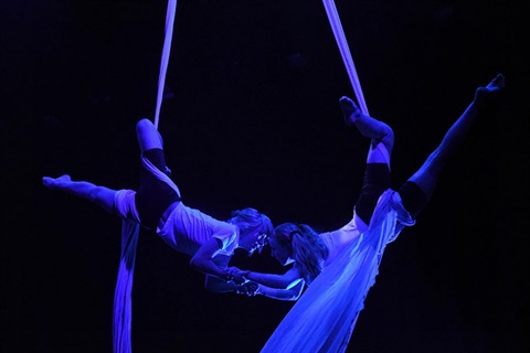 two young people hanging from ceiling and entwined with long scarves