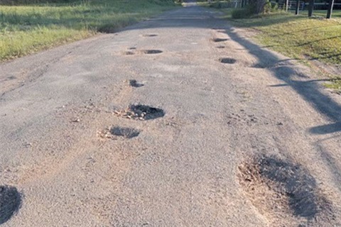 close up of deep potholes on narrow bitumen road