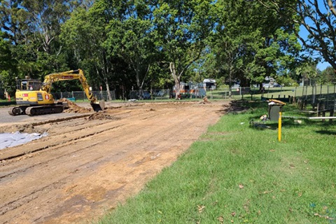 Yellow digger working in gravel area 