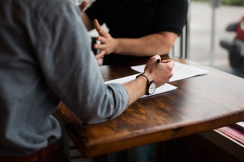 person sitting at desk holding pen and fillng out a form